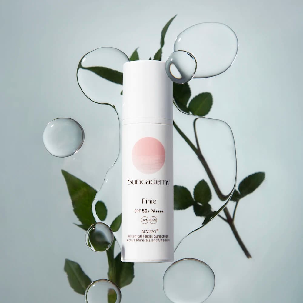 A facial sunscreen bottle arranged with leaves and water drops